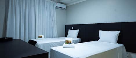 A hotel room with two single beds, a desk, and a chair.