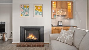 A living room with a fireplace, a sofa, and artwork on the wall. - Wonderful Ocean Block Unit Centrally Located on 70th Street (Ocean City)