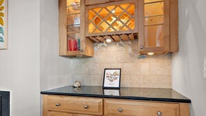 A kitchen with wooden cabinets, a black countertop, and a wine rack above. - Wonderful Ocean Block Unit Centrally Located on 70th Street (Ocean City)