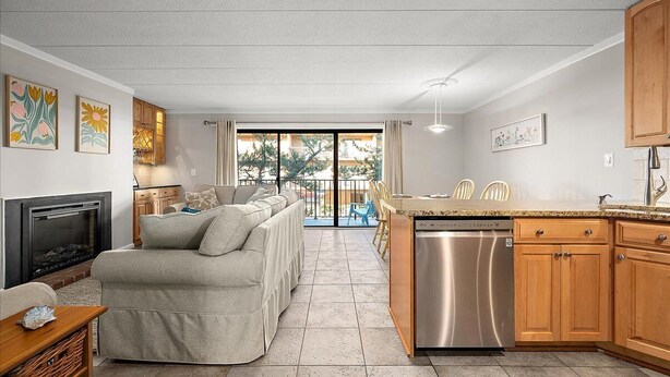 A modern kitchen with a dishwasher, wooden cabinets, and a dining area with chairs. - Wonderful Ocean Block Unit Centrally Located on 70th Street (Ocean City)