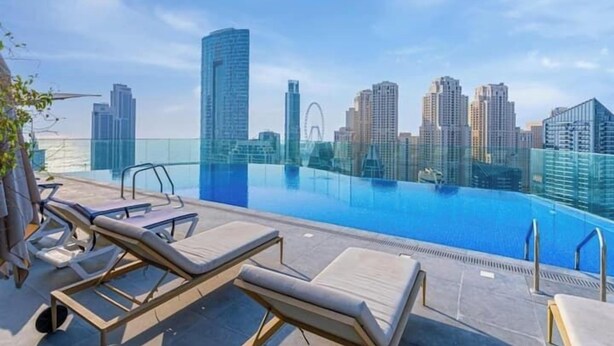 Piscina sul tetto con sedie a sdraio e vista sullo skyline cittadino.