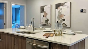 A modern kitchen with a large island, stainless steel appliances, and contemporary artwork on the walls. - Whimsical Rocky Mt. Retreat by Banff National Park (Harvie Heights)