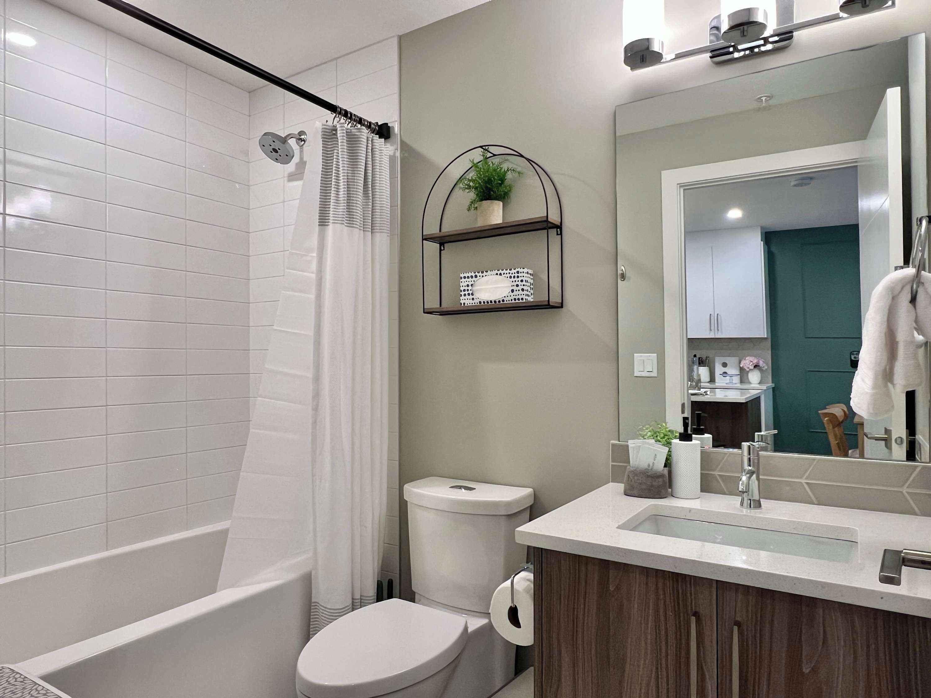 Une salle de bain moderne avec une baignoire blanche, des toilettes et un lavabo surmonté d’un miroir.