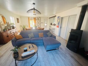 Sala de estar com sofá, mesa de centro, lareira e área de jantar ao fundo.