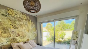 A bedroom with a large bed, a map wall, and a view of the outdoors through a sliding door.