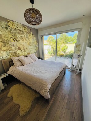 Quarto com cama grande, parede decorada com mapa e vista para o exterior por uma porta deslizante.