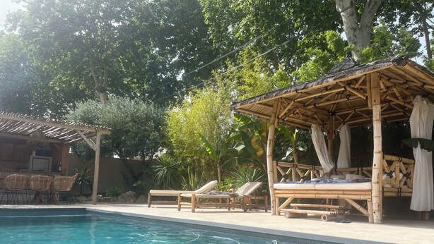 A pool area with lounge chairs, a covered seating area, and a bar.