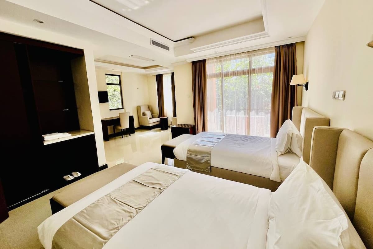 Una habitación de hotel con dos camas, un televisor, un escritorio y una silla.
