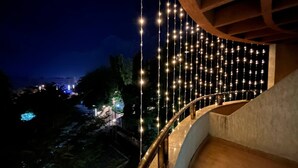 Una escalera curva adornada con luces colgantes, que lleva a un espacio al aire libre con árboles y luces a lo lejos.