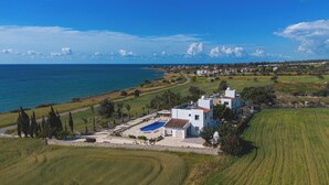 Una propiedad costera con piscina, edificios blancos y vistas al mar.