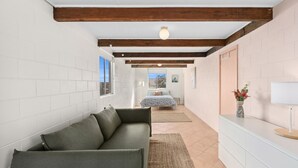 A modern room with a sofa, a bed, and a small table with a vase of flowers. - Gerroa House located mere steps from Seven Mile Beach. (Gerroa)