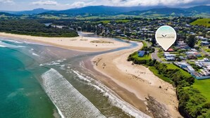 An aerial view of a coastal area with a beach, a river, and a town. - Gerroa House located mere steps from Seven Mile Beach. (Gerroa)