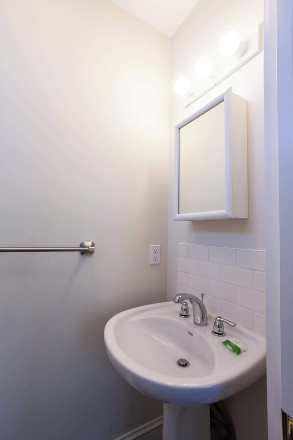 A bathroom with a white sink, a mirror, and a towel rack.