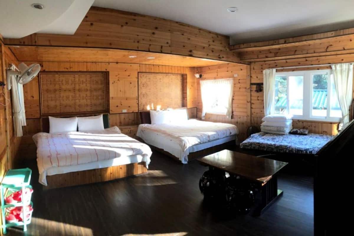 A wooden cabin with three beds, a table, and a window.