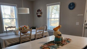 A kitchen with a central island, white cabinetry, and a dining area with a table and chairs.