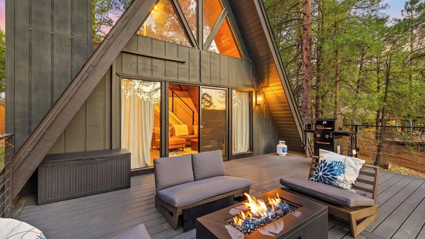 A modern, A-frame wooden cabin with a deck, outdoor seating, and a fire feature. - Kachina A-Frame Hideaway | AC | Hot Tub | Firepit (Flagstaff)