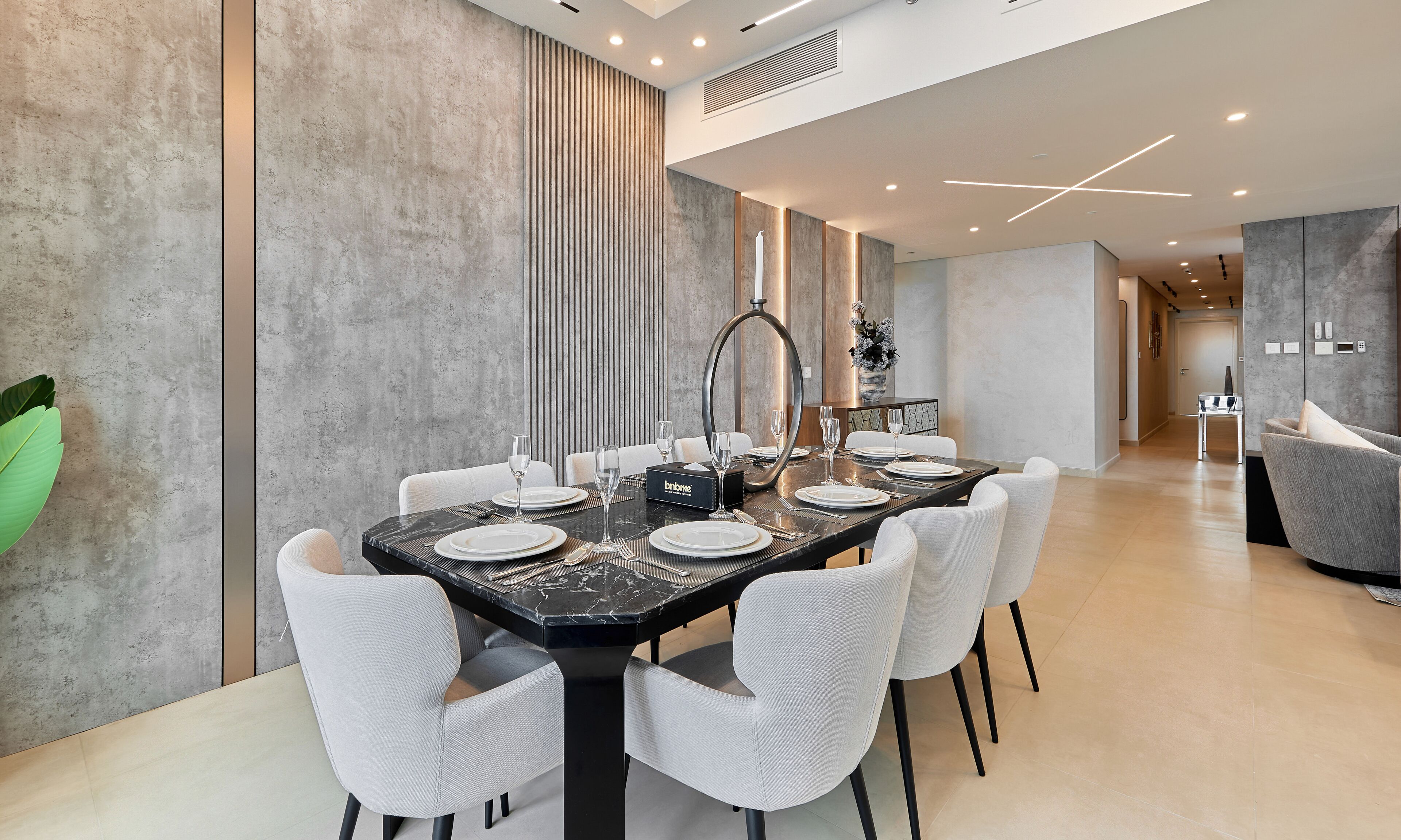 Un espace repas moderne avec une table en marbre, des chaises blanches et un vase de fleurs.