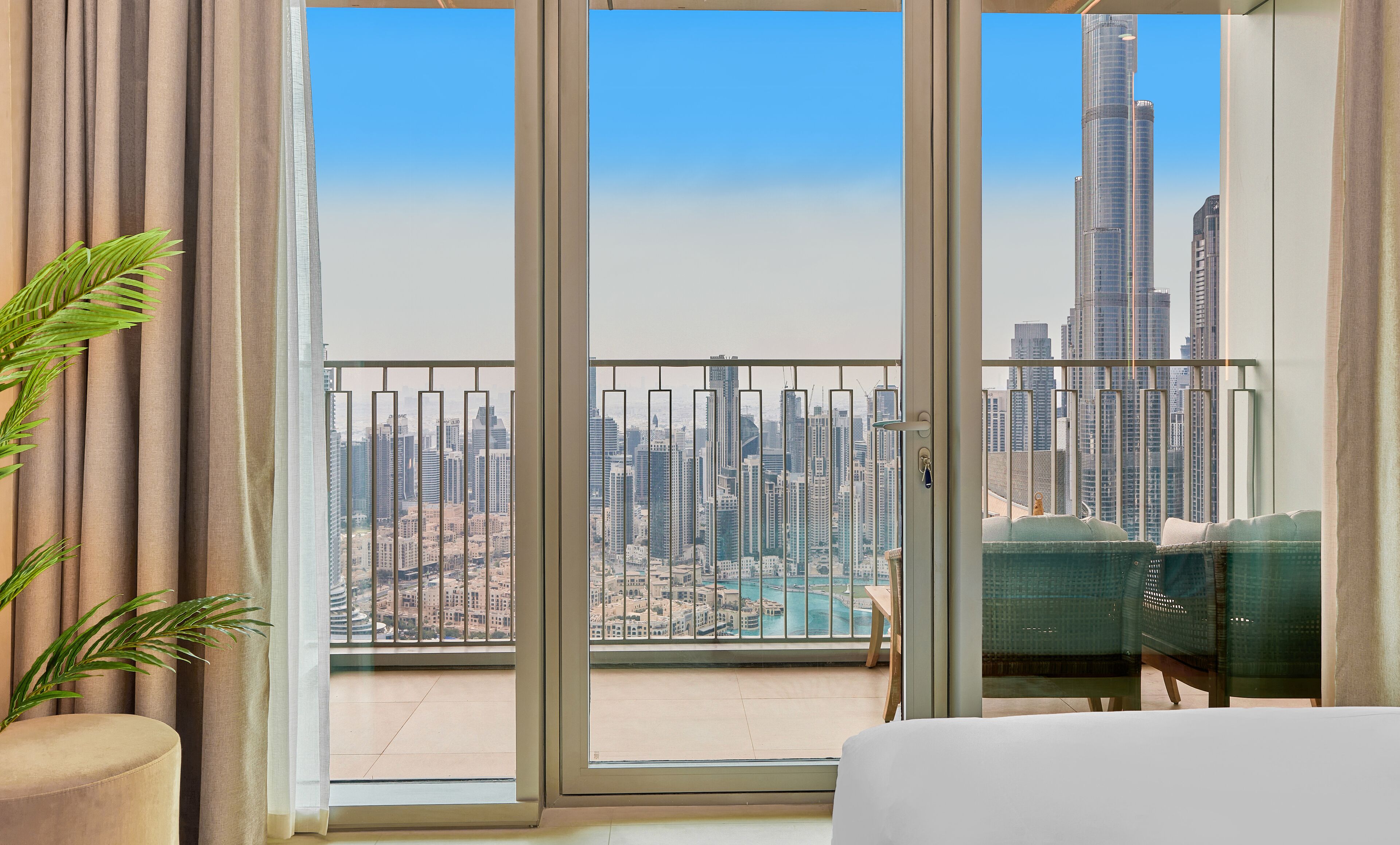 Habitación de hotel con un amplio ventanal corredera que da a un balcón con vistas a la ciudad.