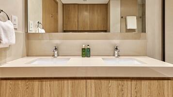 Un baño moderno con dos lavamanos, armarios de madera y un espejo grande.