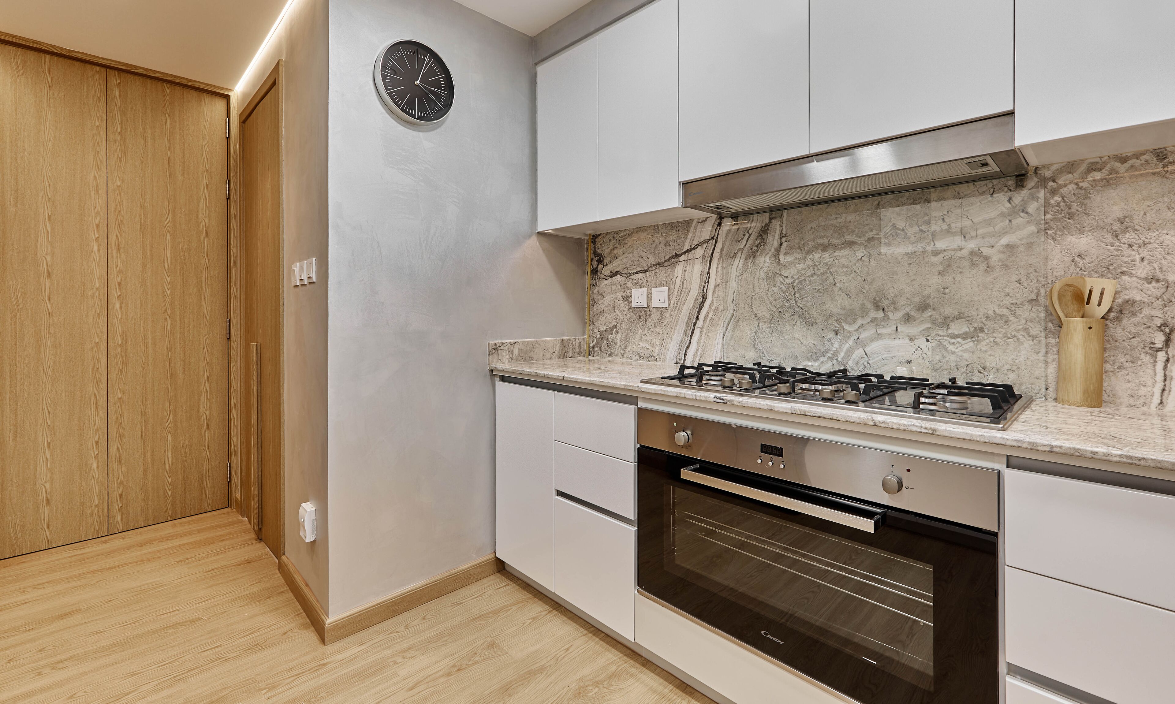 A modern kitchen with a gas stove, oven, and marble backsplash.