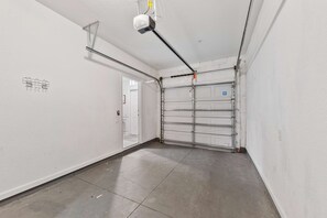 A clean, empty hallway with a garage door, a ceiling-mounted projector, and a door leading to another room. - Modern 3BR Townhome near Orlando Top Attractions (Orlando)
