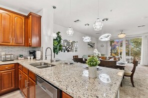 A modern kitchen with granite countertops, wooden cabinets, and stainless steel appliances.