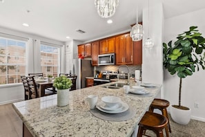A modern kitchen with granite countertops, wooden cabinets, stainless steel appliances, and pendant lighting. - Modern 3BR Townhome near Orlando Top Attractions (Orlando)