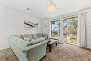 A living room with a sectional sofa, a coffee table, and a chandelier.