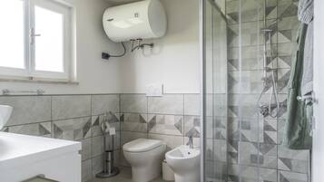 Une salle de bain moderne équipée de toilettes, d’un bidet et d’une douche.