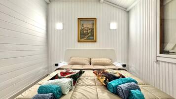Ein Schlafzimmer mit Bett, Kissen, einem Gemälde und einem Fenster.