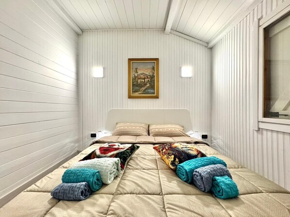 A bedroom with a bed, pillows, a painting, and a window. - MONFERRATO VACATIONS VACATION HOME (Ottiglio)