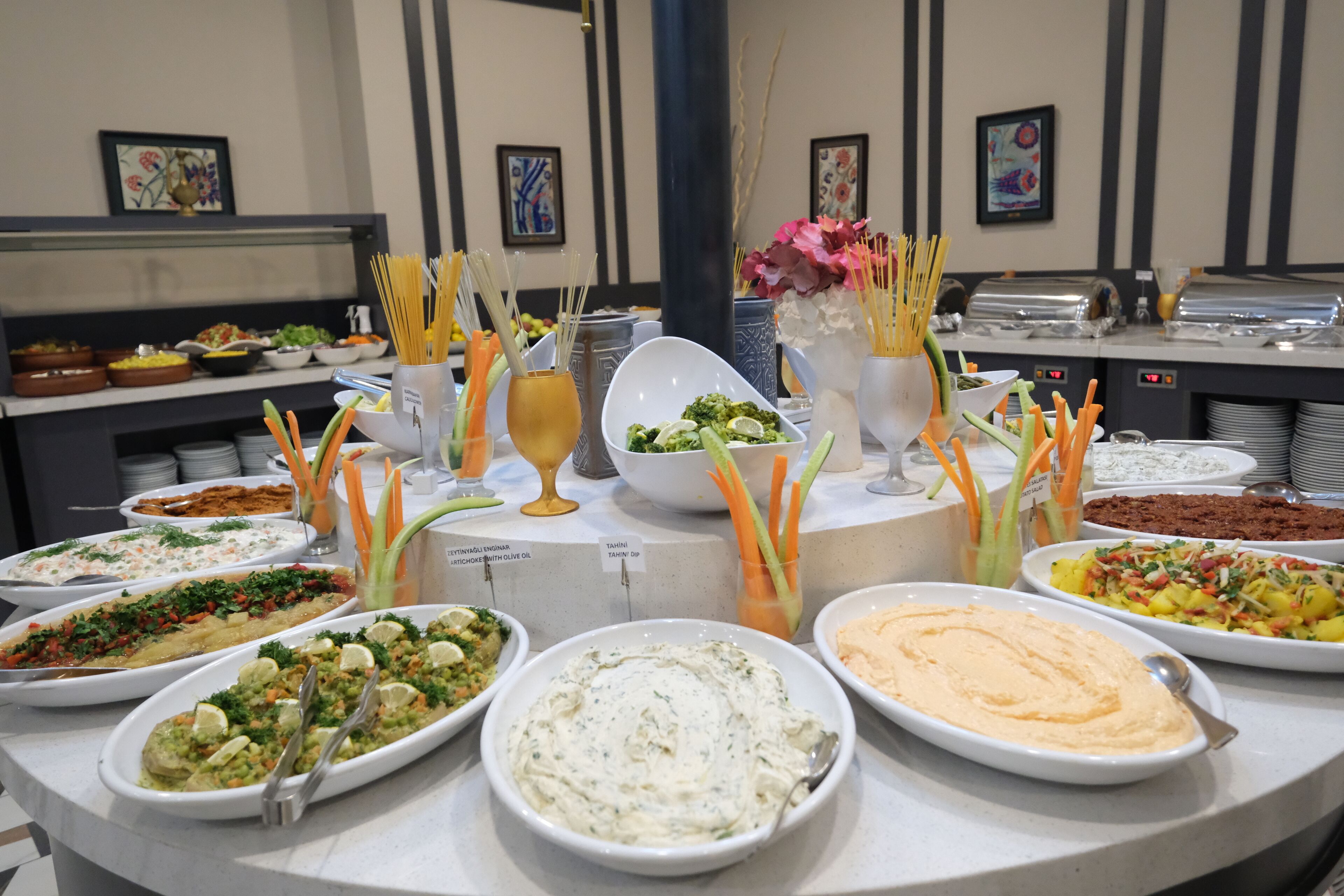A buffet table with various dishes, including dips, salads, and pasta, arranged on a marble countertop.
