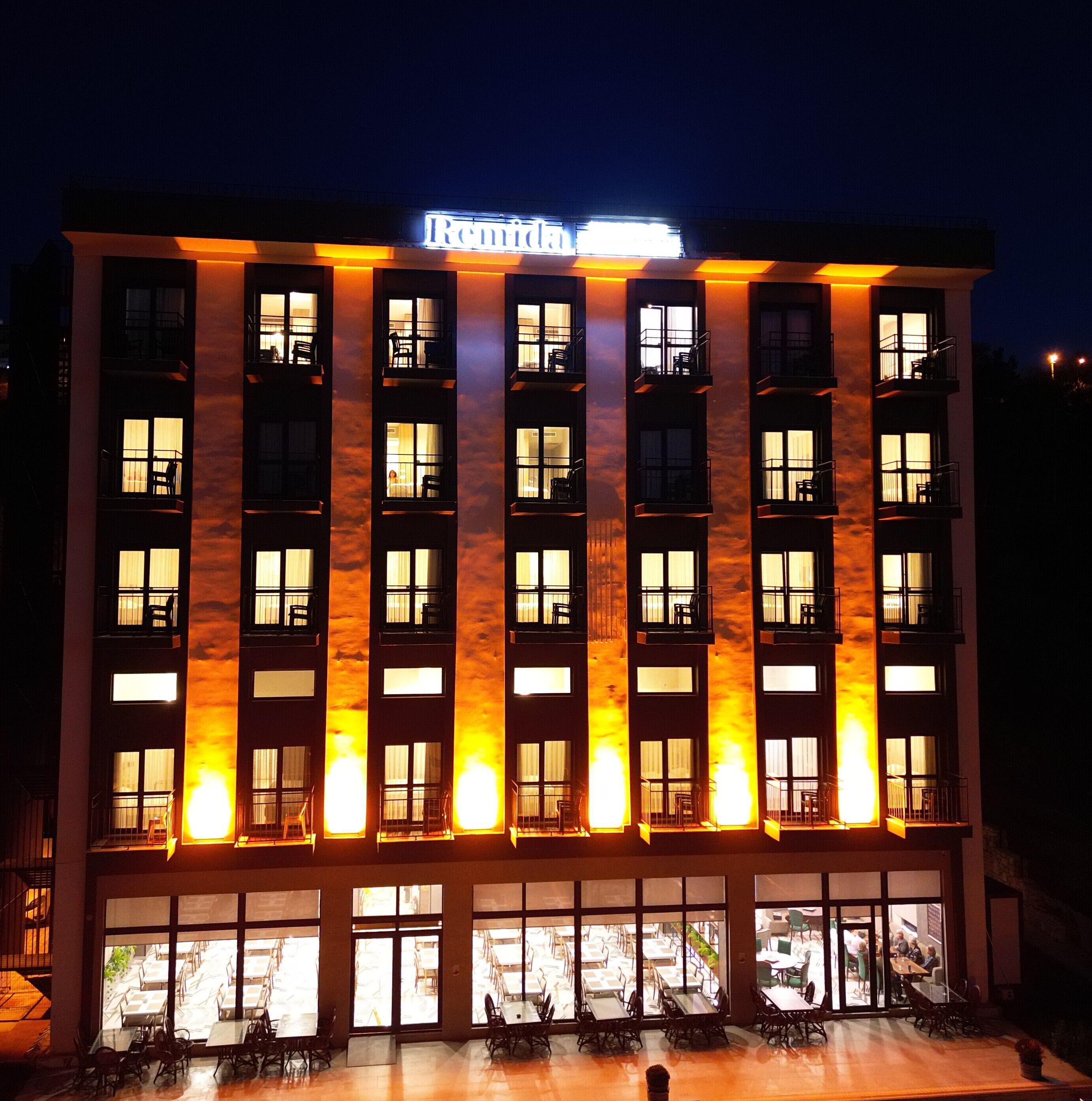 Un hotel de varios pisos con ventanas iluminadas y un cartel que dice "Remi".