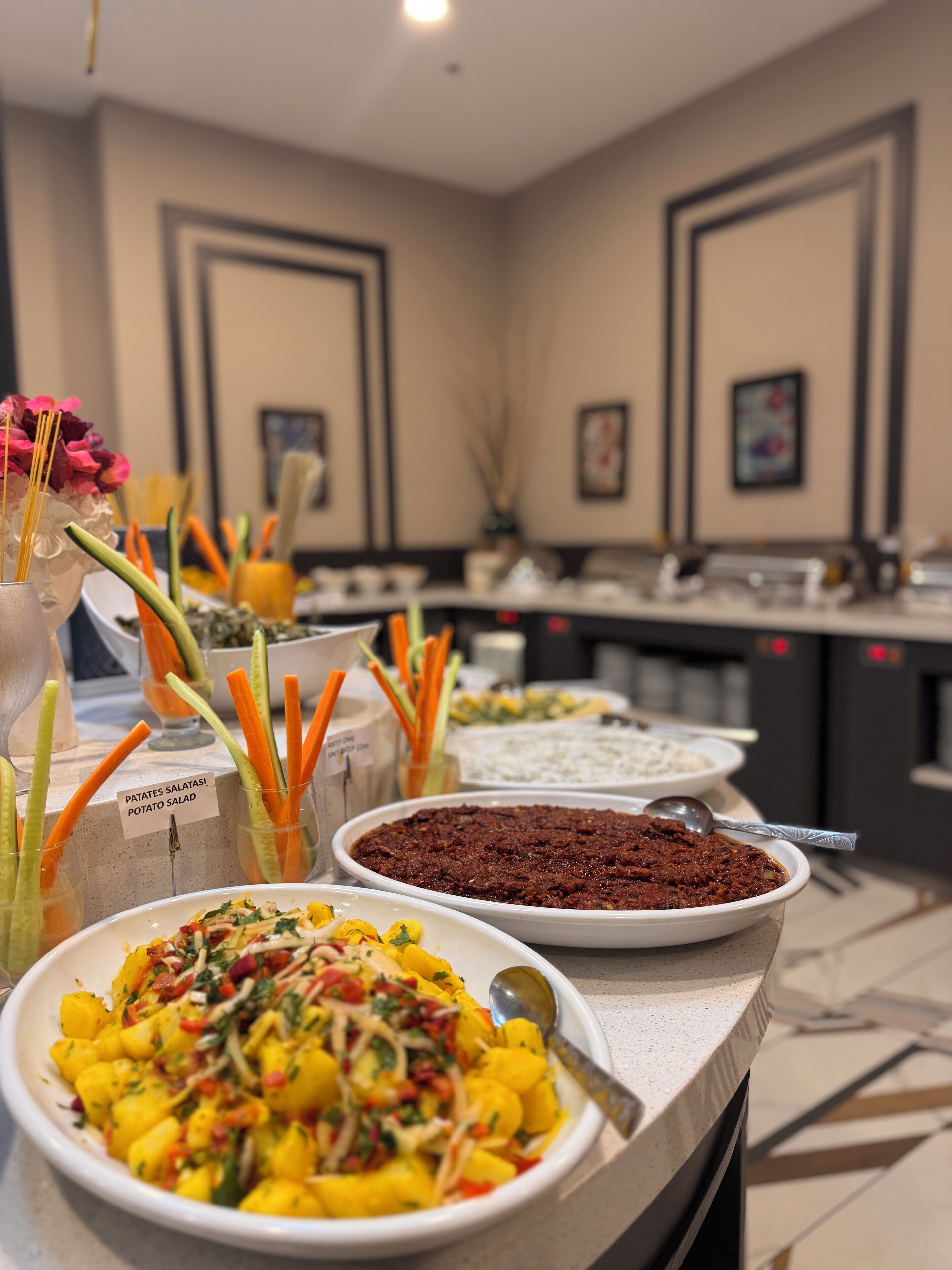 A buffet with various dishes including potato salad, a red sauce dish, and a yellow dish with vegetables.