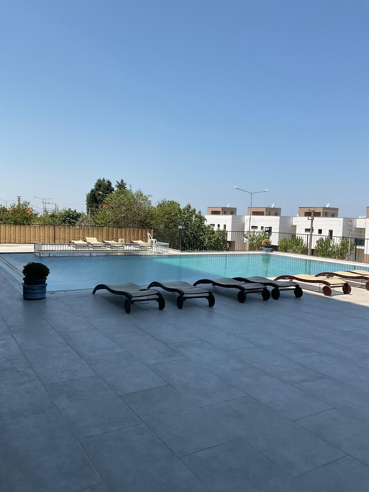 A rooftop swimming pool with lounge chairs and a trash bin.