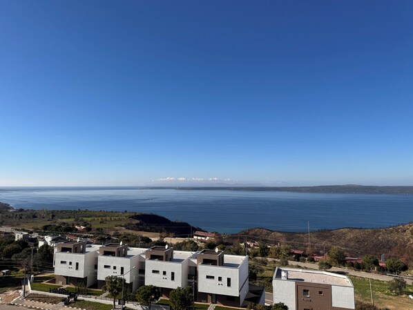 A coastal residential area with modern buildings, a clear view of the sea, and distant mountains. - Remida Managed by Dedeman (Çanakkale)
