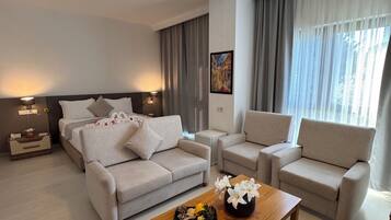 Una sala de estar moderna con un sofá, dos sillones, una mesa de centro y un cuadro en la pared.