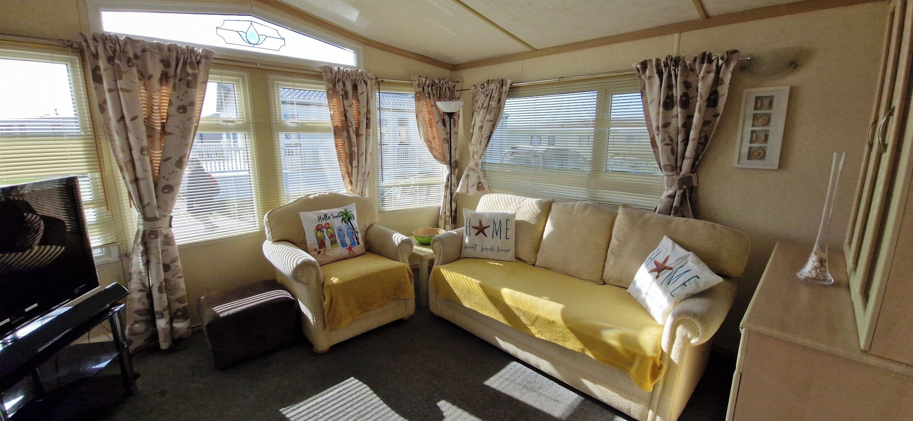 A cozy living area with a sofa, armchairs, a television, and curtains.