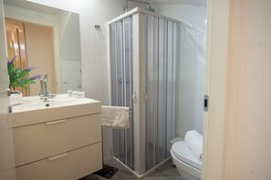 Un baño con cabina de ducha, lavabo con espejo y retrete.