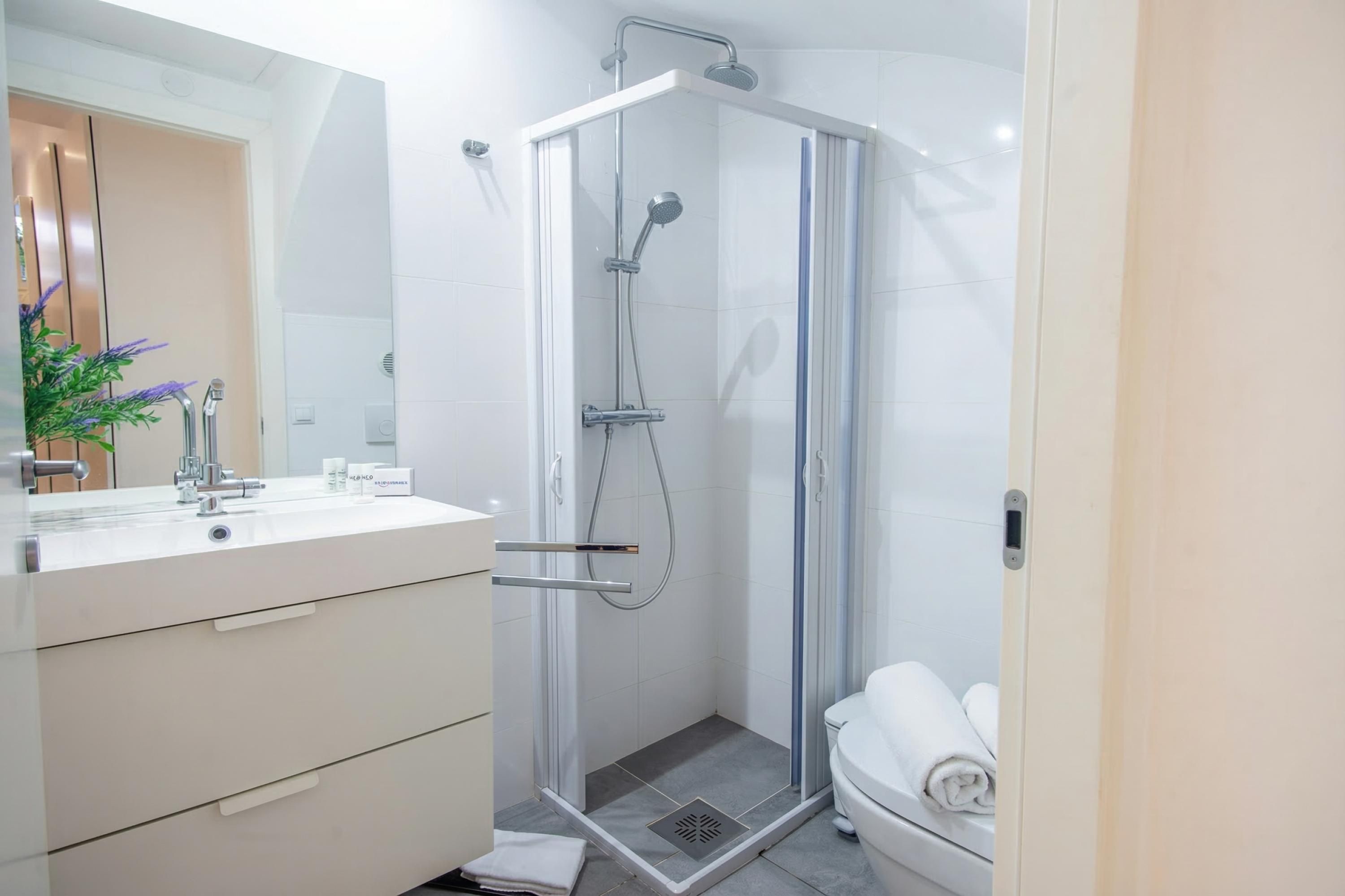 Une salle de bain moderne avec une douche à parois de verre, un meuble-lavabo avec un miroir et des toilettes.