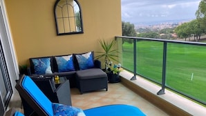 A balcony with two lounge chairs, a sofa, and a potted plant. - Stunning bay views overlooking championship golf course (Lagos)