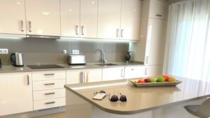 A modern kitchen with white cabinets, a central island, a toaster, and a fruit bowl. - Stunning bay views overlooking championship golf course (Lagos)