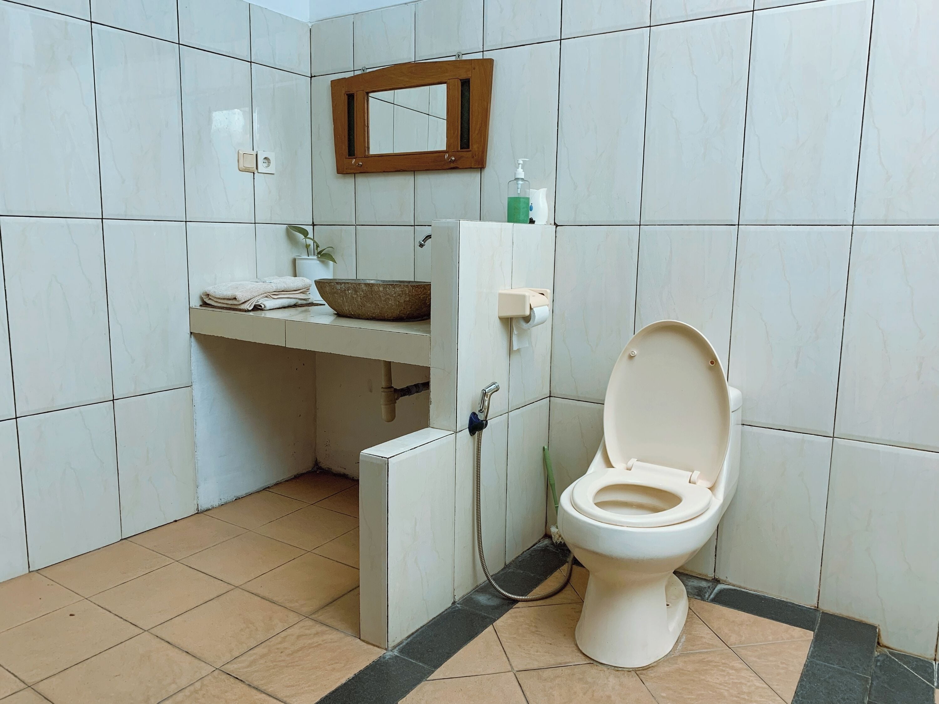 A bathroom with a toilet, sink, and mirror.