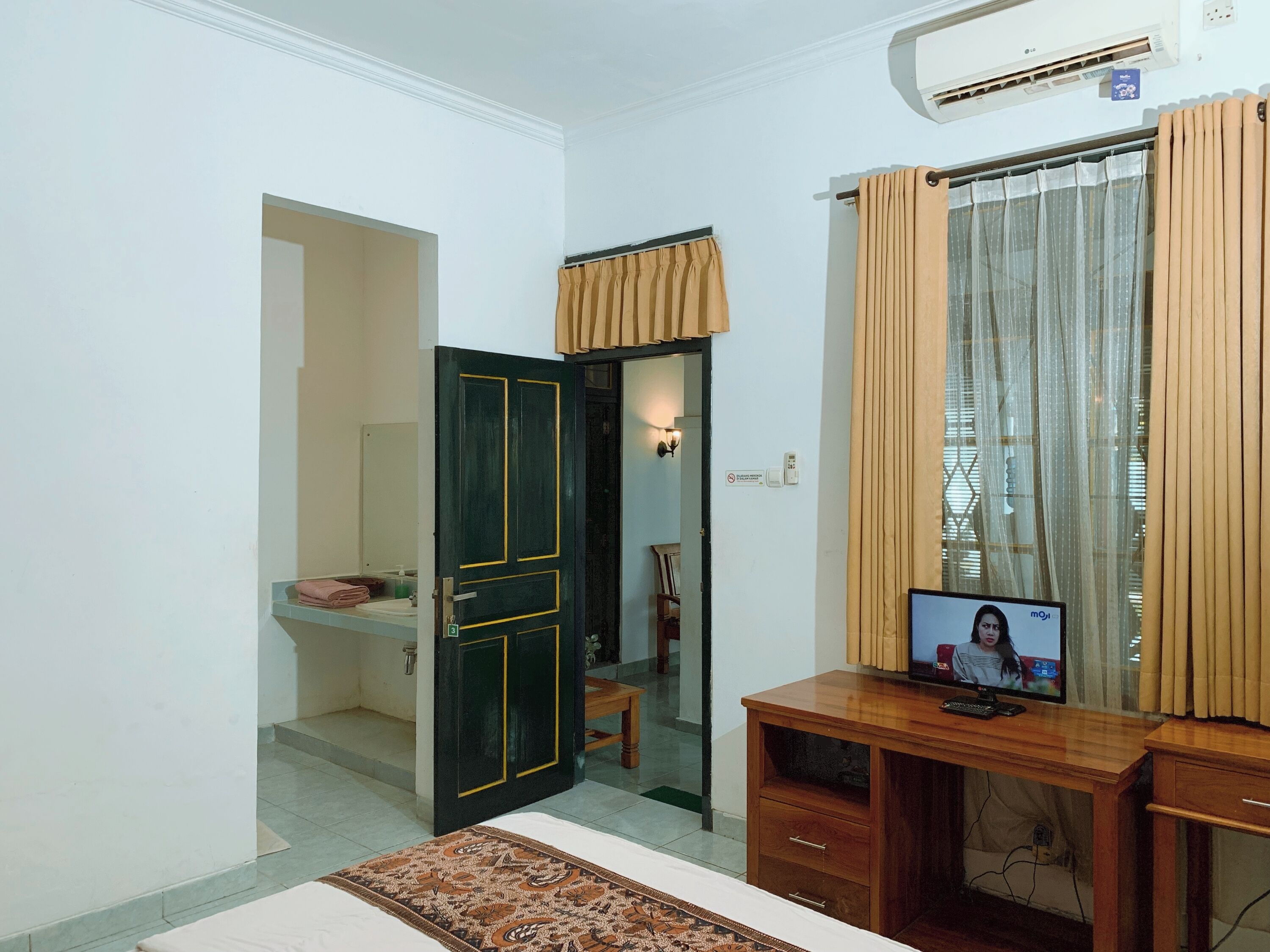 Une chambre comprenant un lit, un bureau avec un ordinateur, une armoire et un miroir.