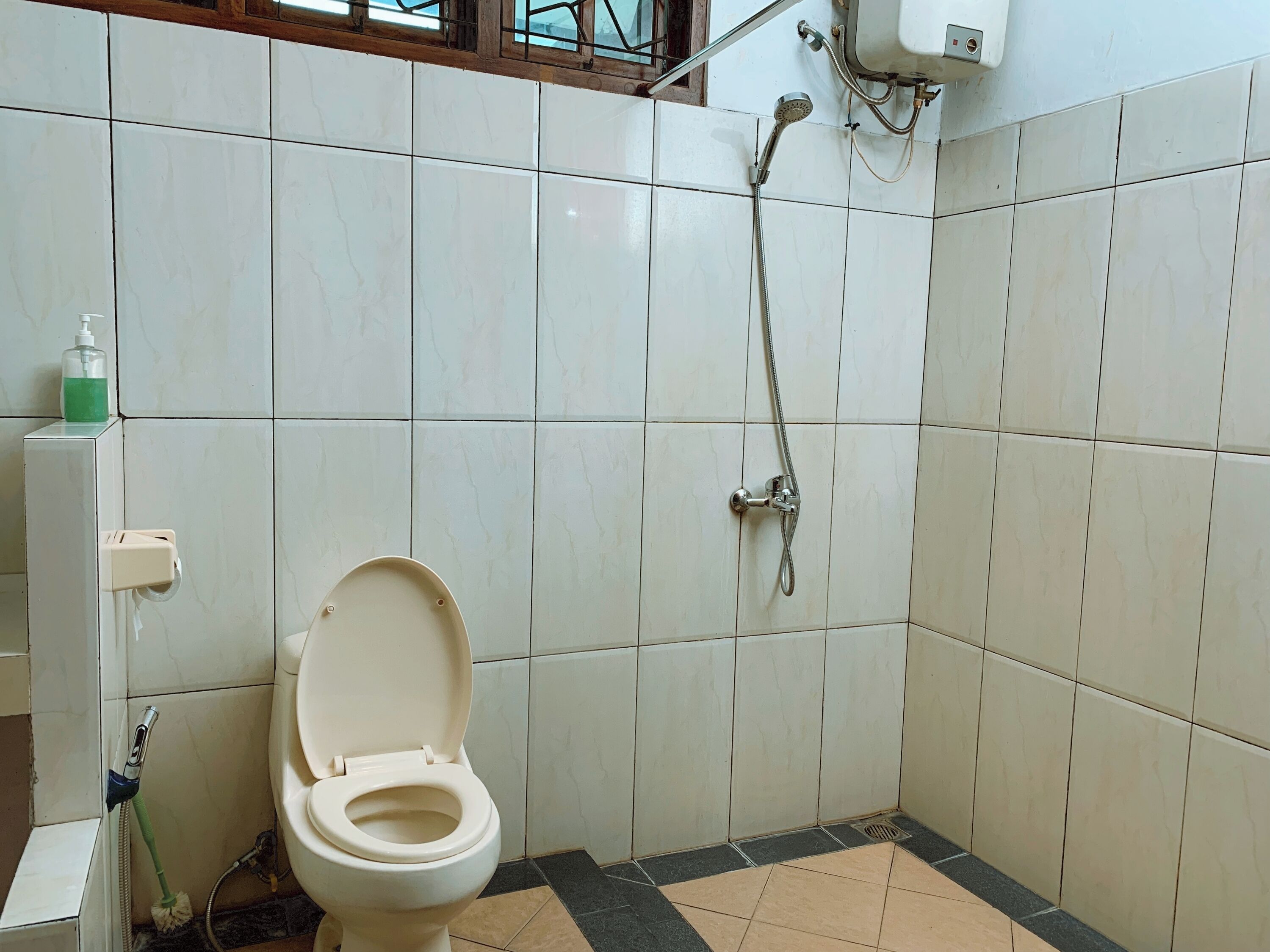 Un baño con inodoro, ducha y dispensador de jabón.