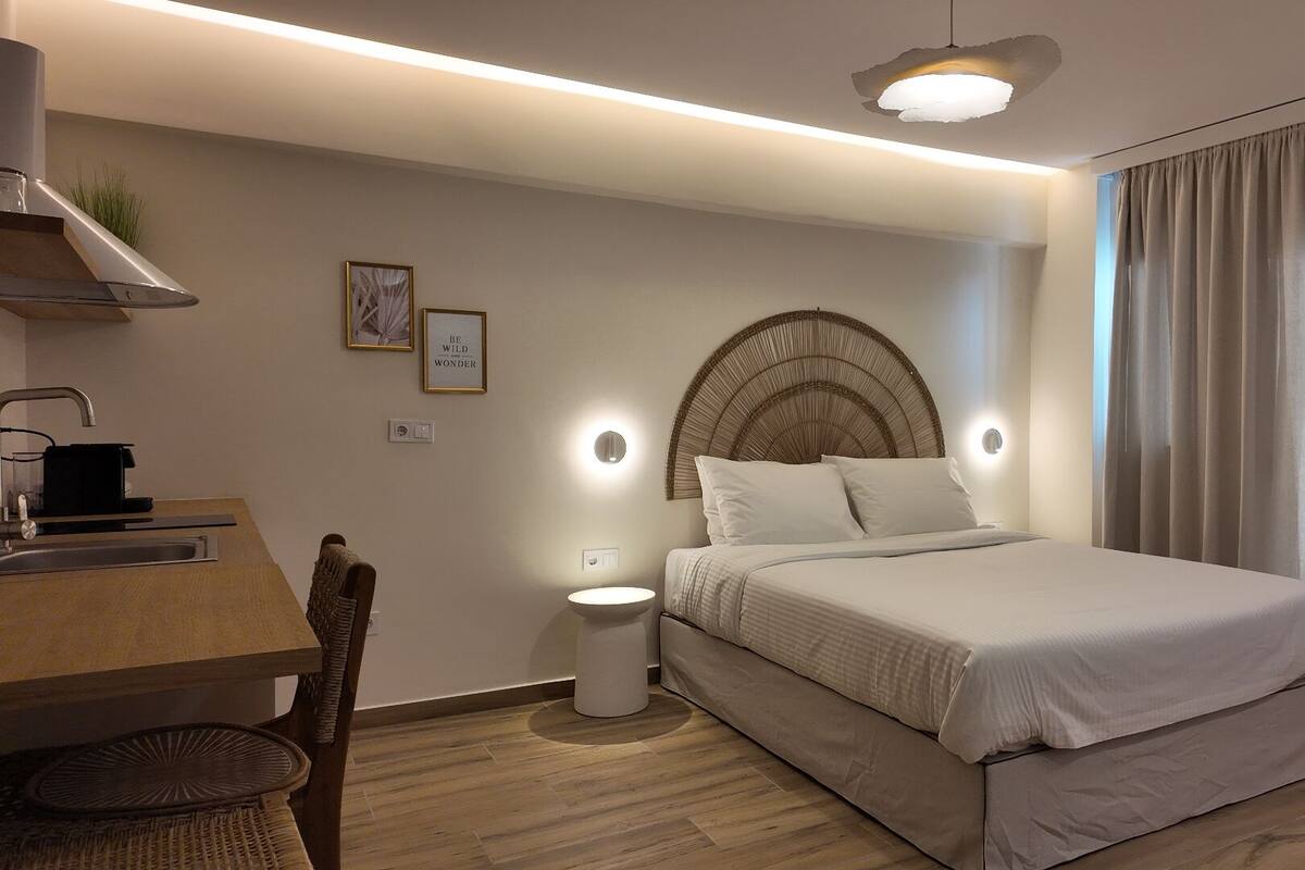 A modern bedroom with a bed, bedside table, and a desk with a chair.