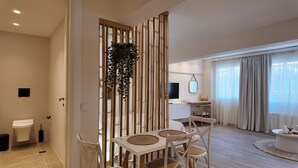Ett modernt vardagsrum med en matplats, en TV som är monterad på väggen och ett stort fönster med gardiner.