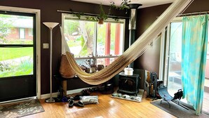 A cozy room with a hammock, a fireplace, and a view of the outdoors.