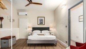 A modern bedroom with a bed, bedside lamps, a ceiling fan, and a framed artwork on the wall. - Lo Studio di Angelique - Florence Dolce Vita (Florence)