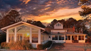 A two-story house with a large glass windowed room and a covered porch. - All Year Retreat - Indoor Heated Pool, Beach, Game & Movie Cottage, Sleeps 21 (Hague)